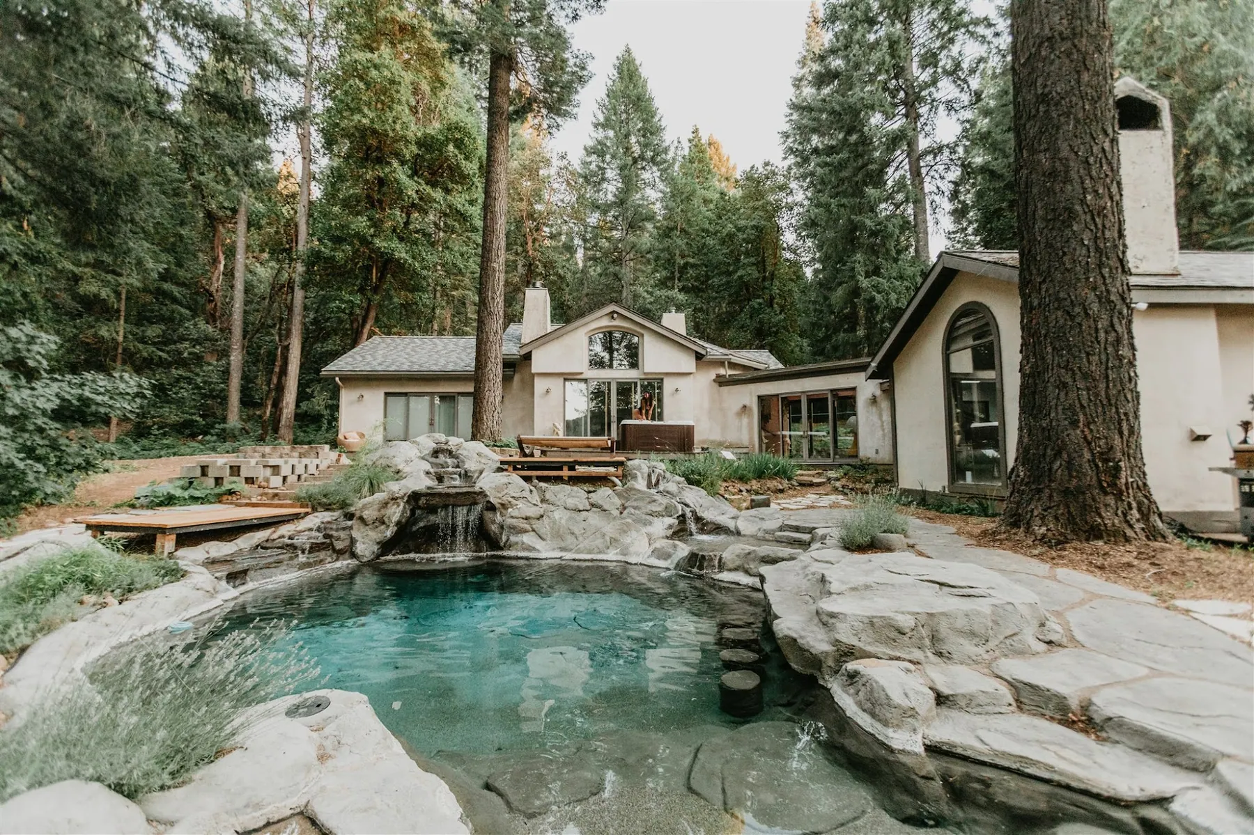 The natural saltwater rock pool and its waterfalls beside the lodge, ringed by tall pines